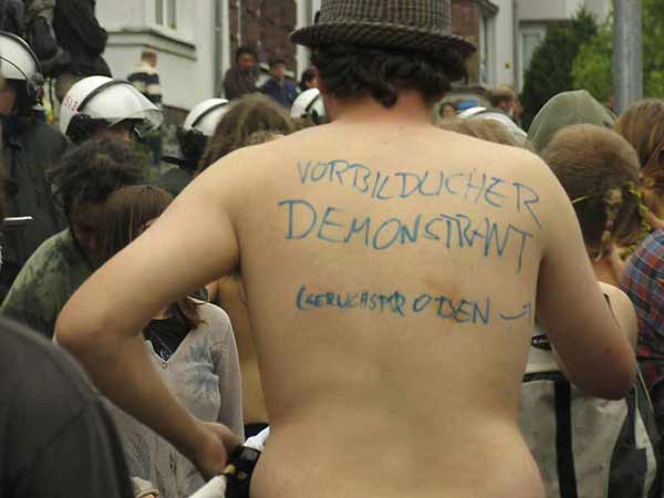Demonstrant von hinten mit freiem Oberkörper mit Rückentext bei G8 in Rostock